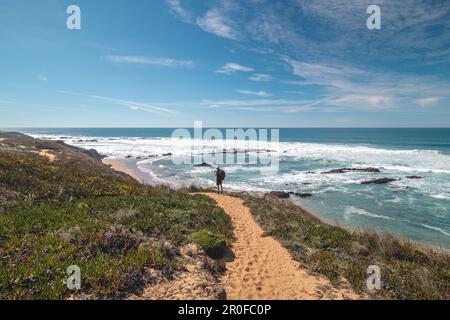 Il viaggiatore cammina su un sentiero sabbioso durante una giornata di sole nella regione di Odemira, Portogallo occidentale. Passeggiando lungo il sentiero dei pescatori, Rota Vicentina. Foto Stock