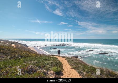 Il viaggiatore cammina su un sentiero sabbioso durante una giornata di sole nella regione di Odemira, Portogallo occidentale. Passeggiando lungo il sentiero dei pescatori, Rota Vicentina. Foto Stock