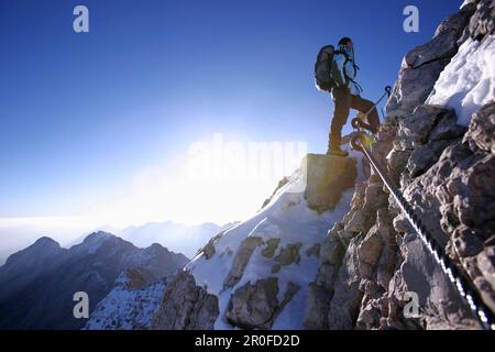 Uomo che cammina fino alla cima dello Zugspitze al mattino, Baviera, Germania Foto Stock