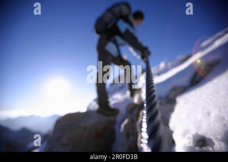 Uomo che cammina fino alla cima dello Zugspitze al mattino, Baviera, Germania Foto Stock
