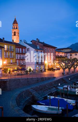 Porto e lungomare con guglia della chiesa Santi Pietro Paolo sullo sfondo in serata, Ascona, Lago maggiore, Ticino, Svizzera Foto Stock