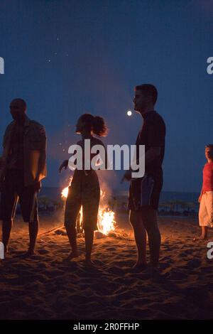 I giovani in piedi sulla spiaggia vicino a un falò, festa domenicale al Sundance Beach Bar, Gennadi Beach, Gennadi, Rodi, Grecia Foto Stock