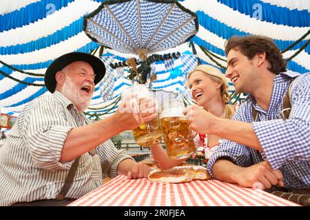 Giovane e un uomo maturo il tintinnio dei bicchieri in una tenda di birra Foto Stock