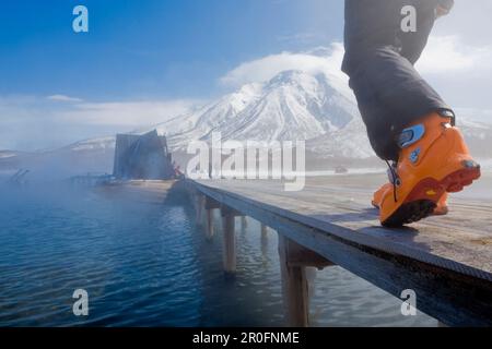 Persona che indossa scarponi da sci a piedi su ponte di legno, penisola di Kamchatka, Sibiria, Russia Foto Stock