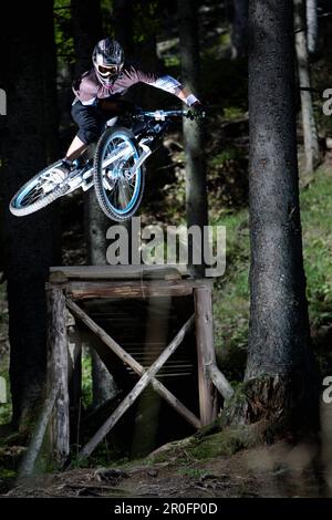 Mountain Biker salto da una rampa, Oberammergau, Baviera, Germania Foto Stock