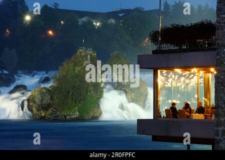 Cascate del Reno di notte, gli ospiti in un ristorante in primo piano, Neuhausen, Canton Sciaffusa, Svizzera Foto Stock