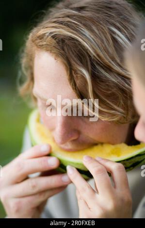 Giovane uomo e donna che condividono un melone, coppia, alta Baviera, Baviera, Germania Foto Stock