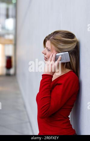 Donna di mezza età a parlare su un telefono mobile, Pinakothek der Moderne di Monaco di Baviera, Germania Foto Stock