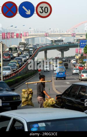 L'uomo sta trasportando la lettura pesante attraverso il rushhour delle strade di Chongqing, Cina, Asia Foto Stock