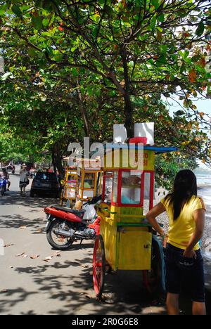 Una donna che si trova accanto a una bancarella di cibo sul lato della strada, Candi Dasa, Bali orientale, Indonesia, Asia Foto Stock