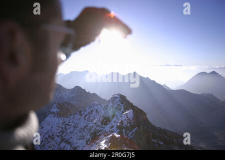 Uomo sulla cima del monte Zugspitze guardando la vista, Baviera, Germania Foto Stock