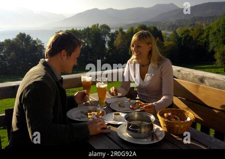 Coppia giovane in un giardino della birra sotto la luce diretta del sole, il lago Tegernsee, Baviera, Germania, Europa Foto Stock