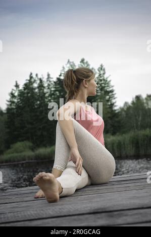 Giovane donna che si allunga sul molo del lago di Starnberg, Baviera, Germania Foto Stock