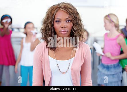 Non so quanto più a lungo posso prendere questo lavoro ... ritratto di un insegnante serio-osservante con i suoi studenti in background. Foto Stock