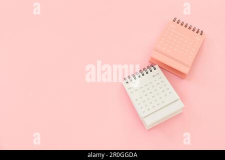 Capovolgere i calendari cartacei su sfondo rosa Foto Stock