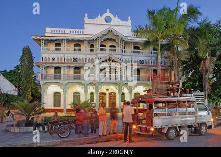 Le persone di fronte alla vecchia farmacia al crepuscolo, Mizingani Road, Stonetown, città di Zanzibar, Zanzibar, Tanzania Africa Foto Stock