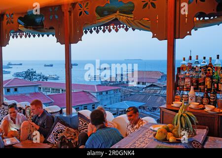 Le persone sulla terrazza sul tetto del Hurumzi hotel in serata, Stonetown, città di Zanzibar, Zanzibar, Tanzania Africa Foto Stock