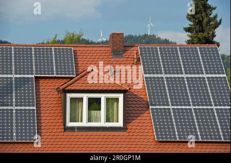 Impianti solari sul tetto di una casa privata e turbine eoliche sullo sfondo, Friburgo in Breisgau, Baden-Wuerttemberg, Germania, Europa Foto Stock