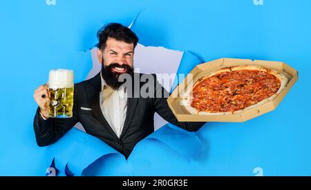 Pizza tempo. Felice uomo al barbuto con pizza e birra tazza guardando attraverso la carta. Ristorante o pizzeria. Fast food. Cucina italiana. Uomo d'affari con pizza Foto Stock