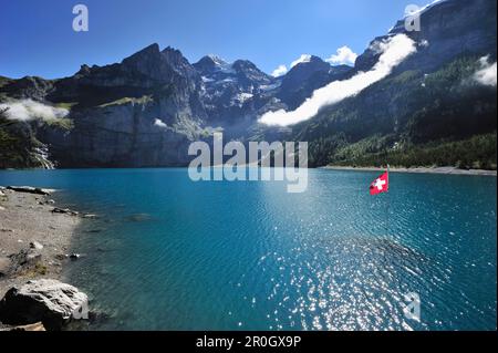 Bandiera svizzera sul lago di Oeschinen, Bluemlisalp, patrimonio dell'umanità dell'UNESCO, area protetta Jungfrau-Aletsch, Oberland Bernese, cantone di Berna, Svizzera Foto Stock