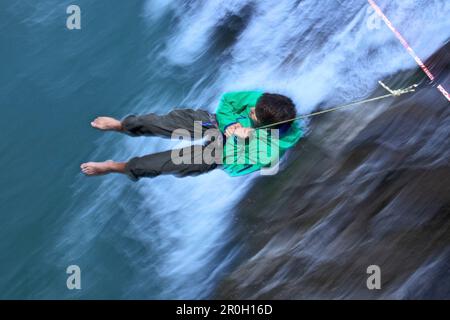 Giovane uomo che ha una pausa dopo non è riuscito ad equilibrarsi su una linea alta sopra un flusso, Fuessen, Baviera, Germania, Europa Foto Stock