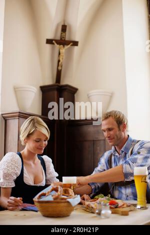 Giovane coppia in costumi tradizionali con uno spuntino in un ristorante Foto Stock