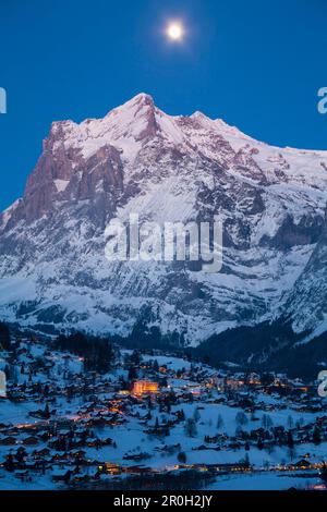 Crepuscolo e Luna piena sopra Grindelwald e il Wetterhorn, stazione sciistica invernale nella Jungfrauregion, Oberland Bernese, Canton Berna, Svizzera, Europa Foto Stock