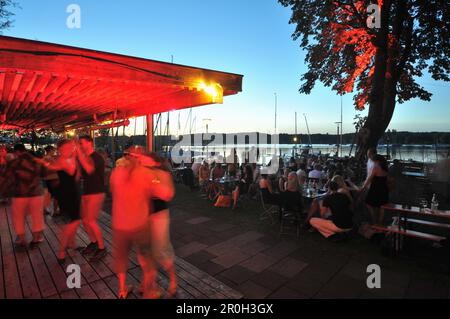 Persone che ballano sulla riva del lago Ammersee al tramonto, Herrsching, alta Baviera, Germania, Europa Foto Stock