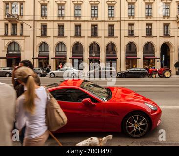 Ferrari rossa e trattore in via Maximilian, shopping ragazza con cane, Monaco, alta Baviera, Baviera, Germania Foto Stock