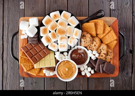 Piatto di spugnole. Marshmallows arrosto, cracker, cioccolato e un gruppo di ingredienti. Vista dall'alto su uno sfondo di legno scuro. Foto Stock