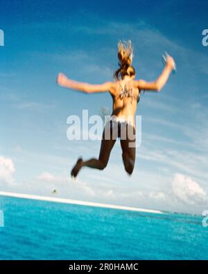 Isole Figi, Northern Lau isole, una giovane donna salta fuori di una parte superiore di uno yacht nell'Oceano Pacifico del Sud Foto Stock