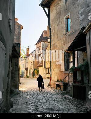 FRANCIA, Borgogna, donna anziana a piedi sul sentiero da edifici, vista posteriore, Noyers Foto Stock