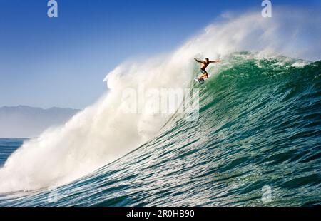 USA, Hawaii, l'uomo surfa una grande onda su una barriera corallina esterna, la North Shore di Oahu Foto Stock