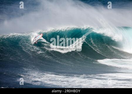 Stati Uniti d'America, Hawaii Maui, un uomo surf sulle onde enormi in corrispondenza di una interruzione chiamati ganasce o Peahi Foto Stock