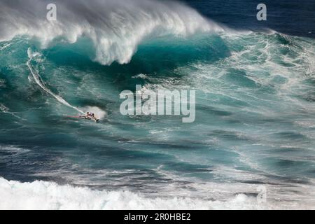 Stati Uniti d'America, Hawaii Maui, un uomo surf sulle onde enormi in corrispondenza di una interruzione chiamati ganasce o Peahi Foto Stock