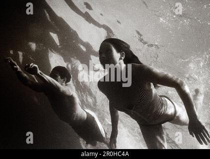 MESSICO, Baja, uomo e donna che nuotano nel Pacifico, Cabo San Lucas (B&W) Foto Stock