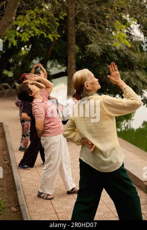 Il Vietnam, Hanoi, donne praticare il tai chi al mattino presto, il Lago Hoan Kiem Foto Stock