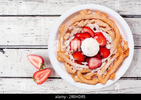 Vista dall'alto della torta con imbuto di fragole su uno sfondo di legno bianco. Tradizionale fiera estiva. Foto Stock