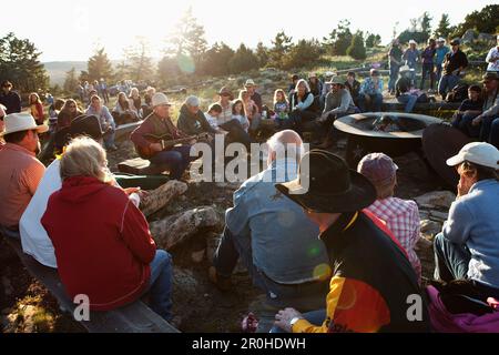 Stati Uniti d'America, Wyoming Encampment, gli ospiti di un dude ranch sedersi intorno a un falò e ascoltare un uomo suonare la chitarra e cantare canzoni country western, Abara Ranch Foto Stock