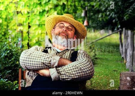 Hobby giardiniere seduto su una sedia nel suo giardino, dormire, Germania Foto Stock