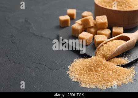 Zucchero di canna su tavola nera, primo piano. Spazio per il testo Foto Stock