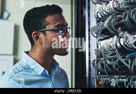 Che cosa sta succedendo qui. un bel giovane tecnico che si alza da solo e guarda il mainframe. Foto Stock