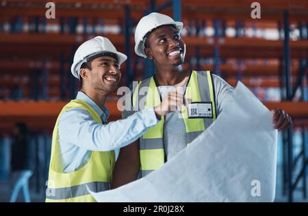 Potremmo spostare alcune cose intorno. due giovani appaltatori in piedi nel magazzino insieme e utilizzando un piano per pianificare. Foto Stock