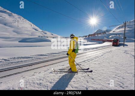 Sciatore accanto a binari ferroviari, Diavolezza, Engadin, Cantone di Graubuenden, Svizzera Foto Stock