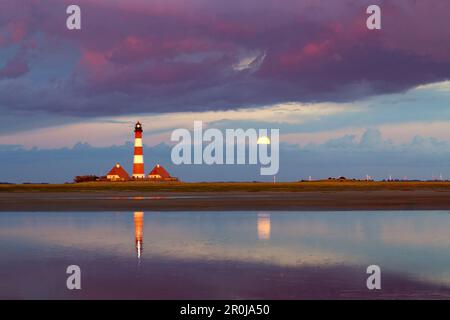 Faro, le nuvole e la luna che riflette in appartamenti vicino a Faro Westerhever, penisola di Eiderstedt, Schleswig-Holstein, Germania Foto Stock