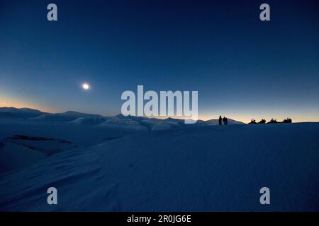 3 persone con motoslitte durante l'eclissi solare totale, Spitzbergen, Svalbard, Norvegia Foto Stock