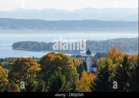 Vista da Ilkahoehe attraverso il lago di Starnberg alle alpi, autunno, cappella con torre a forma di cipolla, vicino a Tutzing, regione dei cinque laghi di Starnberg, Starnberg, B Foto Stock