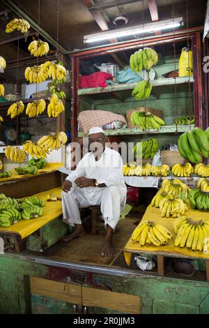 L'uomo vende banane allo stand di frutta al mercato di Mahatma Jyotiba Phule (mercato di Crawford), Mumbai, Maharashtra, India Foto Stock