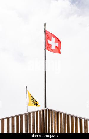 Bandiera svizzera, bandiera della Svizzera che soffia nel vento, Finsteraarhornhut, ghiacciaio di Fiescher, Oberland Berner, Svizzera Foto Stock
