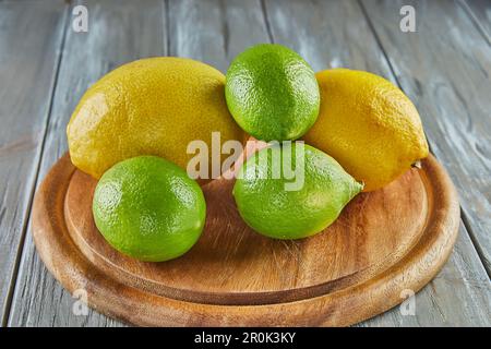 Limoni e lime su legno si trovano su sfondo grigio di legno Foto Stock